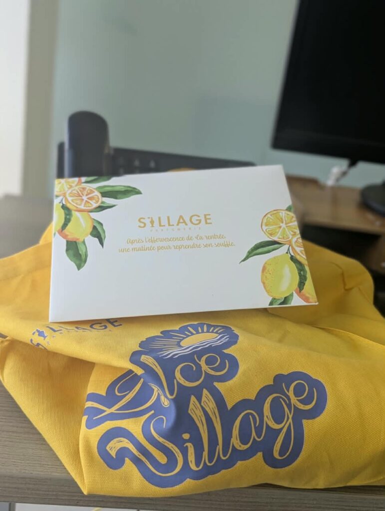 Carte d’invitation Sillage Parfumerie posée sur le tote bag jaune Dolce Sillage